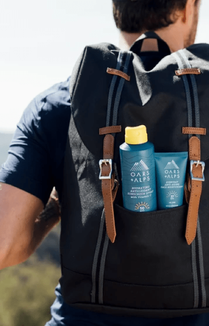 man carrying his oar + alps sunscreen while hiking