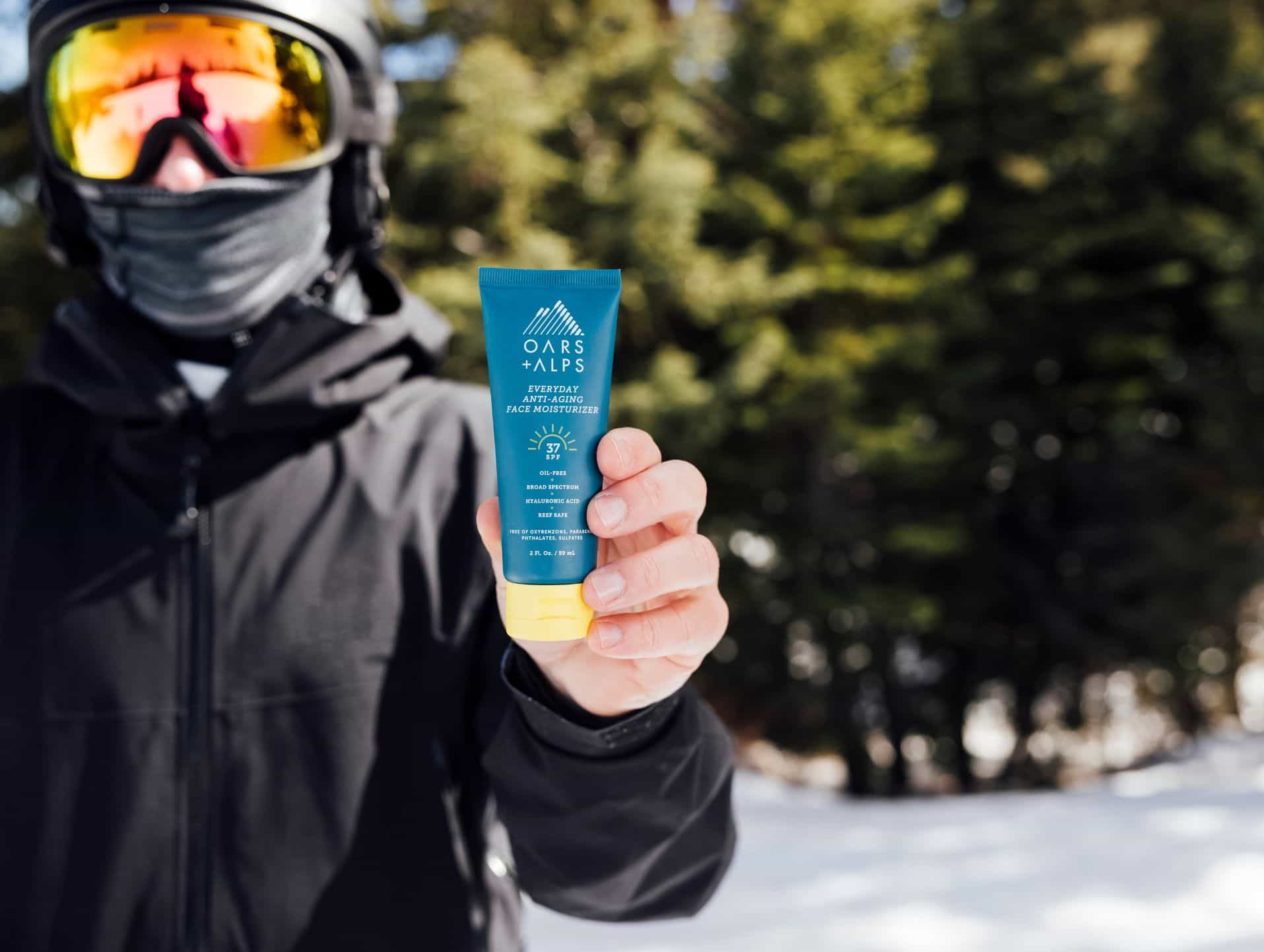 Skiier holding Oars + Alps face moisturizer with SPF